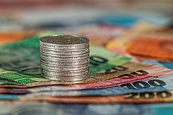 Stack of silver coins on colorful banknotes