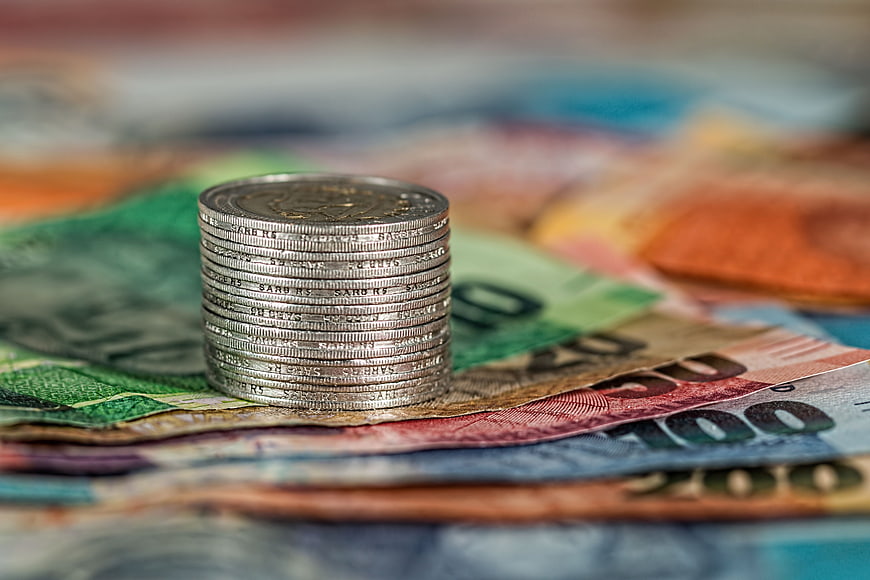 Stack of silver coins on colorful banknotes