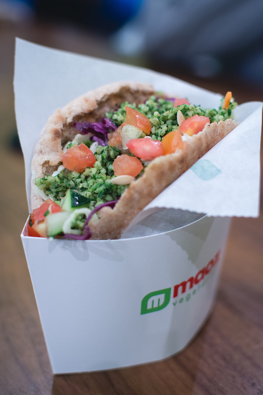 Close-up of fresh falafel wrap with vegetables in paper container