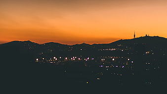 Silhouette of city skyline against vibrant orange sunset sky