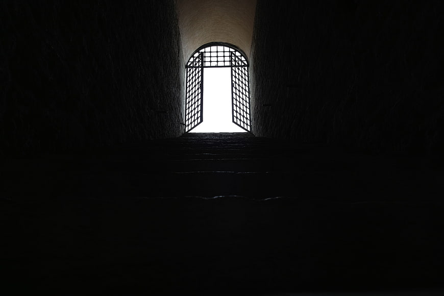 Dark stone staircase leading to bright arched doorway