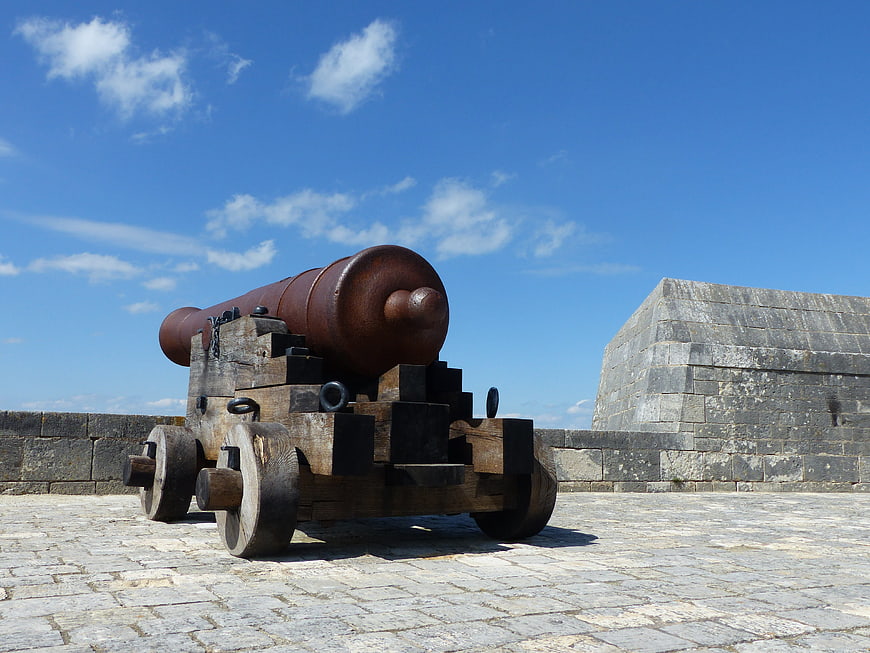Historic cannon on stone fortification ramparts under blue sky