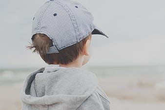 Toddler Boy in Cap Looking at Ocean Beach