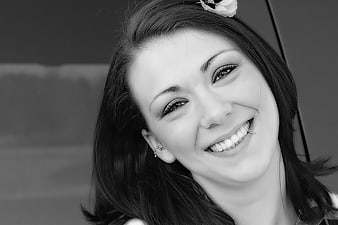 Black and white portrait of smiling woman with flower in hair