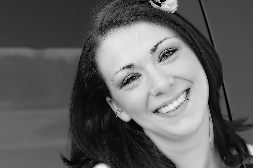 Black and white portrait of smiling woman with flower in hair