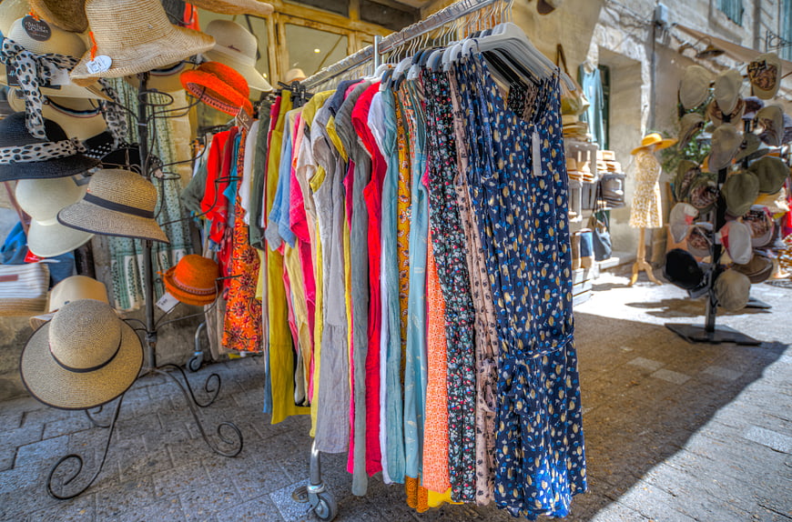 Colorful summer dresses and straw hats on outdoor street market rack