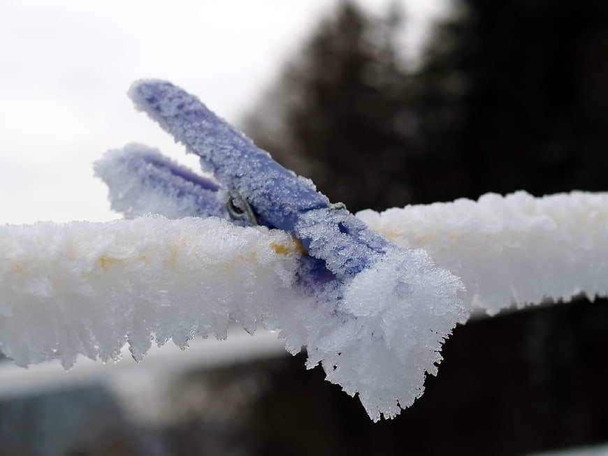 Blue clothespin covered in hoarfrost on a frozen clothesline