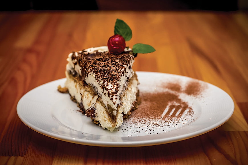 Slice of Tiramisu Cake with Chocolate Shavings on White Plate