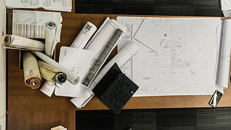 Architectural blueprints and laptop on wooden desk