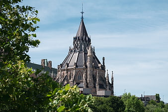 Gothic Revival Architecture Spire with Blue Sky and Green Foliage
