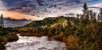 Scenic river flowing through green hills and autumn forest landscape