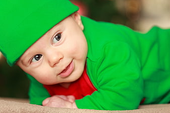 Cute baby boy in green elf costume smiling
