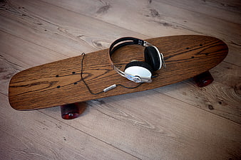 Wooden longboard skateboard with headphones on floor