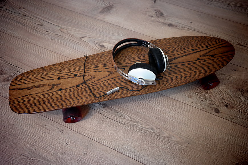 Wooden longboard skateboard with headphones on floor