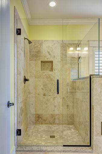 Modern beige marble walk-in shower with glass enclosure