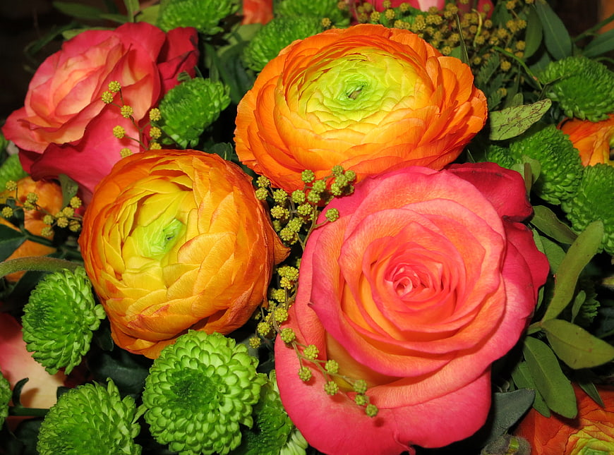 Vibrant bouquet of orange ranunculus and pink roses with green filler