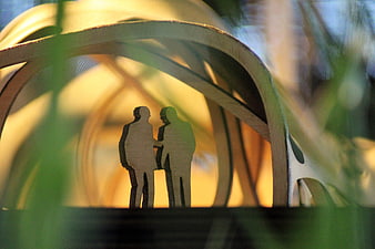 Wooden silhouettes of couple inside architectural model structure