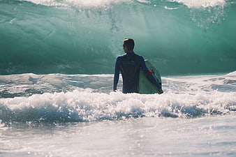 Surfer in Wetsuit Facing Large Ocean Wave