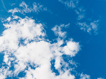 Fluffy white clouds against a vibrant blue sky background