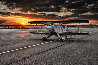 Vintage Biplane on Runway at Dramatic Sunset