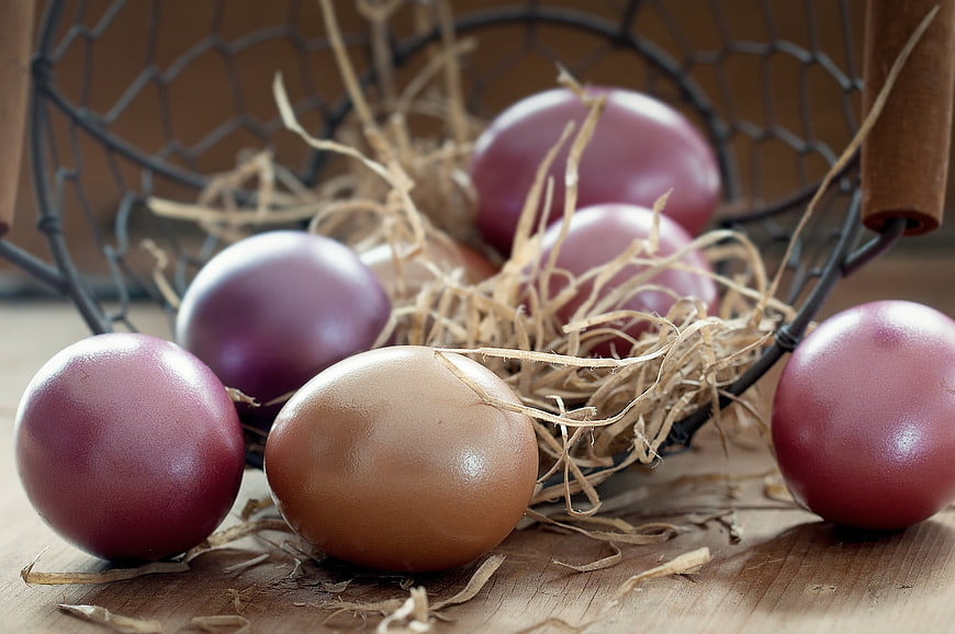 Colored Easter eggs in a wire basket with straw