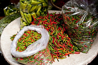 Fresh red and green chili peppers in plastic bags at market