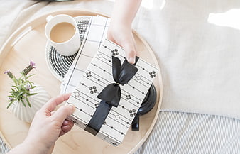 Hands holding gift box on tray with coffee