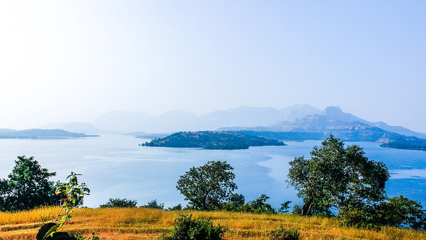 Serene Lake Landscape with Distant Mountains and Foreground Trees