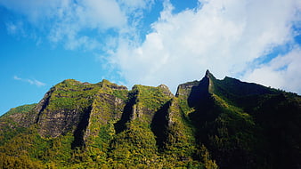 Lush Green Mountain Peaks Under Blue Sky with Clouds