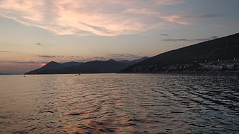 Serene Sea Sunset with Mountain Silhouette and Coastal Village