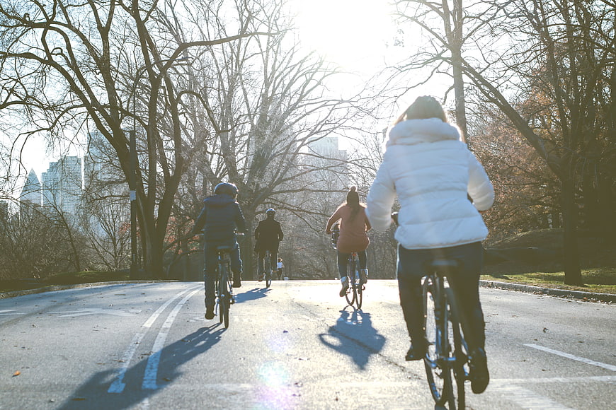 Group of Cyclists Riding on Paved Path in City Park