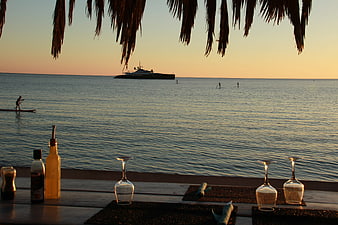 Beachside dining table with wine glasses and sunset ocean view
