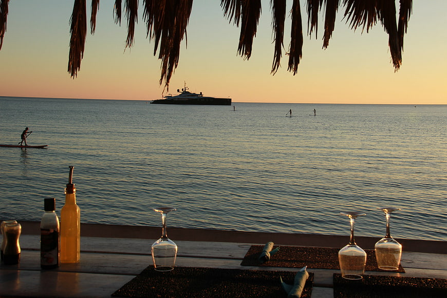 Beachside dining table with wine glasses and sunset ocean view