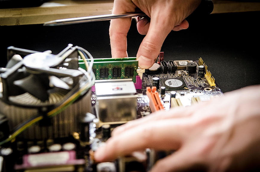 Close-up of hands repairing computer motherboard hardware