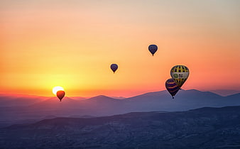 Hot Air Balloons Flying Over Mountains at Sunset