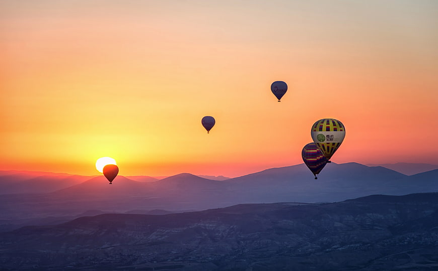 Hot Air Balloons Flying Over Mountains at Sunset