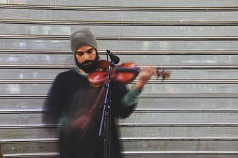 Bearded man playing violin on street with motion blur
