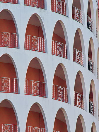White building facade with repeating red arched balconies