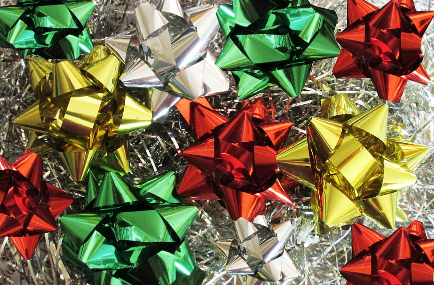 Colorful metallic Christmas gift bows on silver tinsel background