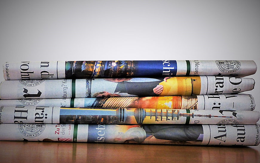 Stack of Rolled German Newspapers on Wooden Table