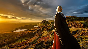 Woman in Medieval Cloak Overlooking Scottish Highlands at Sunset