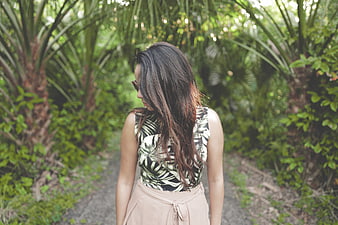 Woman in tropical print top walking on garden path