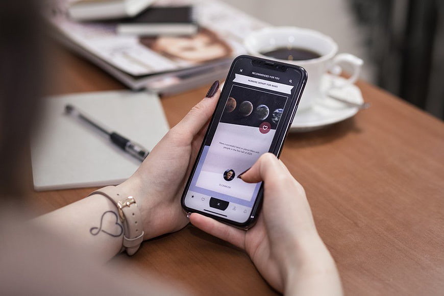 Woman using smartphone app with coffee on wooden table
