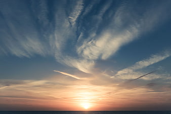 Dramatic Sunset Sky with Wispy Clouds Over Ocean Horizon