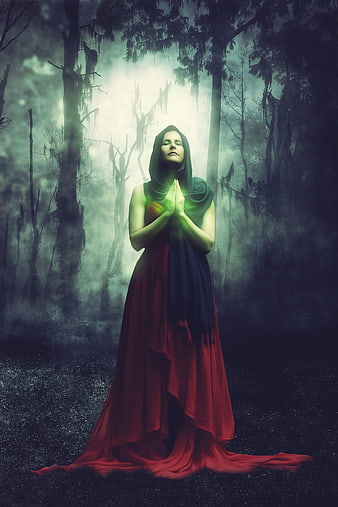 Mystical woman praying in a dark enchanted forest