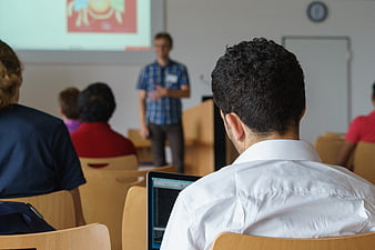 Student attending university lecture with laptop in classroom