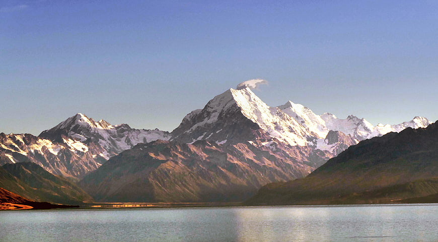 Snow-Capped Mountain Peak Reflected in Calm Lake at Dawn