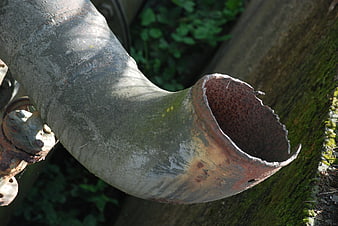 Rusted industrial pipe elbow with jagged broken edge