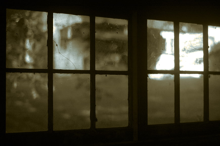 Vintage cracked window panes with sepia tone and dark interior