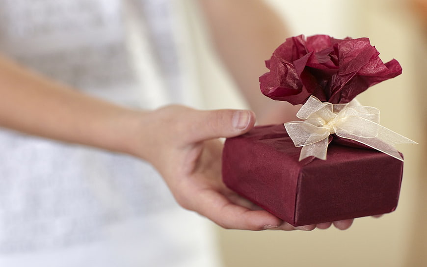 Woman Offering Small Burgundy Gift Box With Tissue Paper